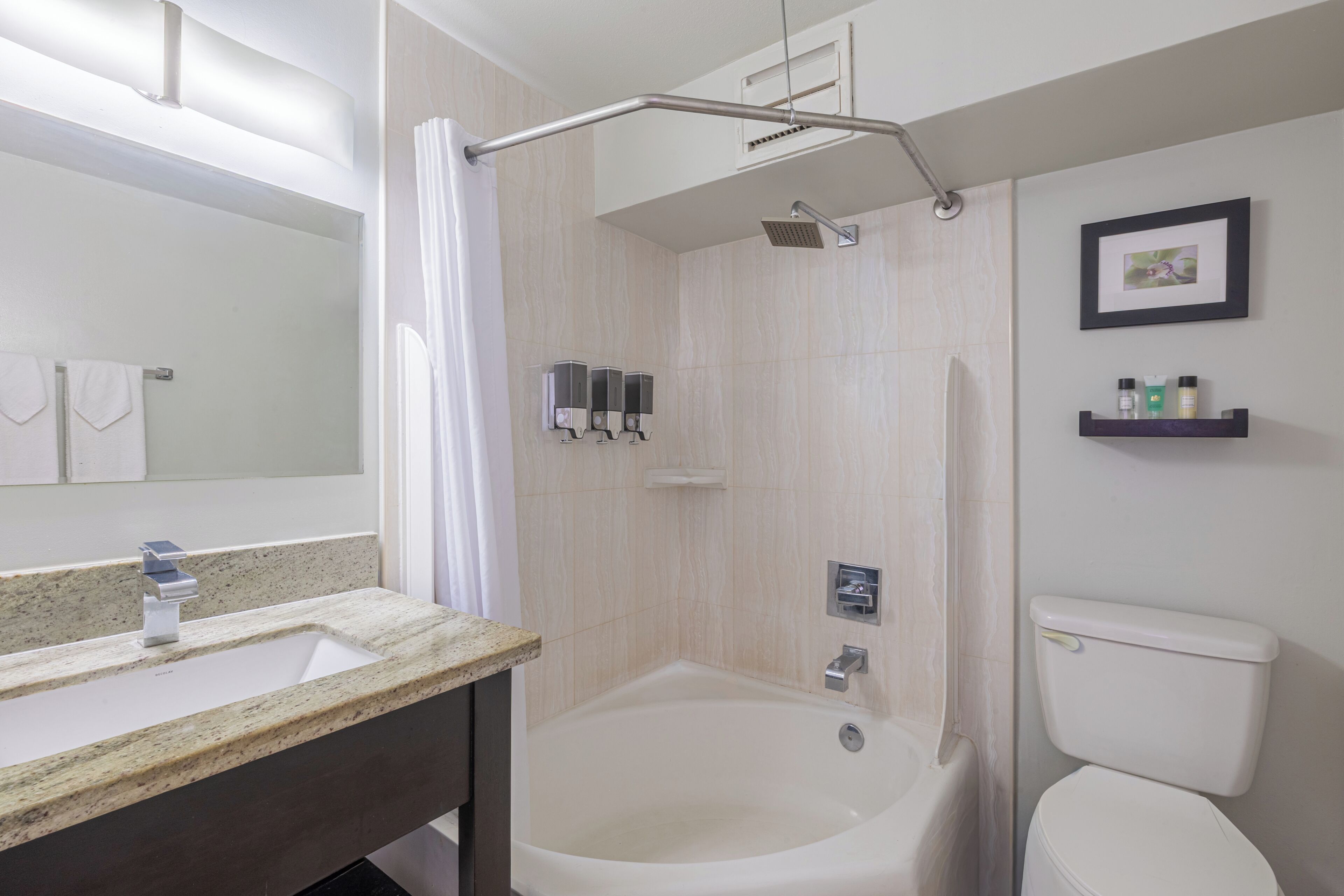 A bathroom with a bathtub, a toilet, a sink with a mirror, and a shower area.
