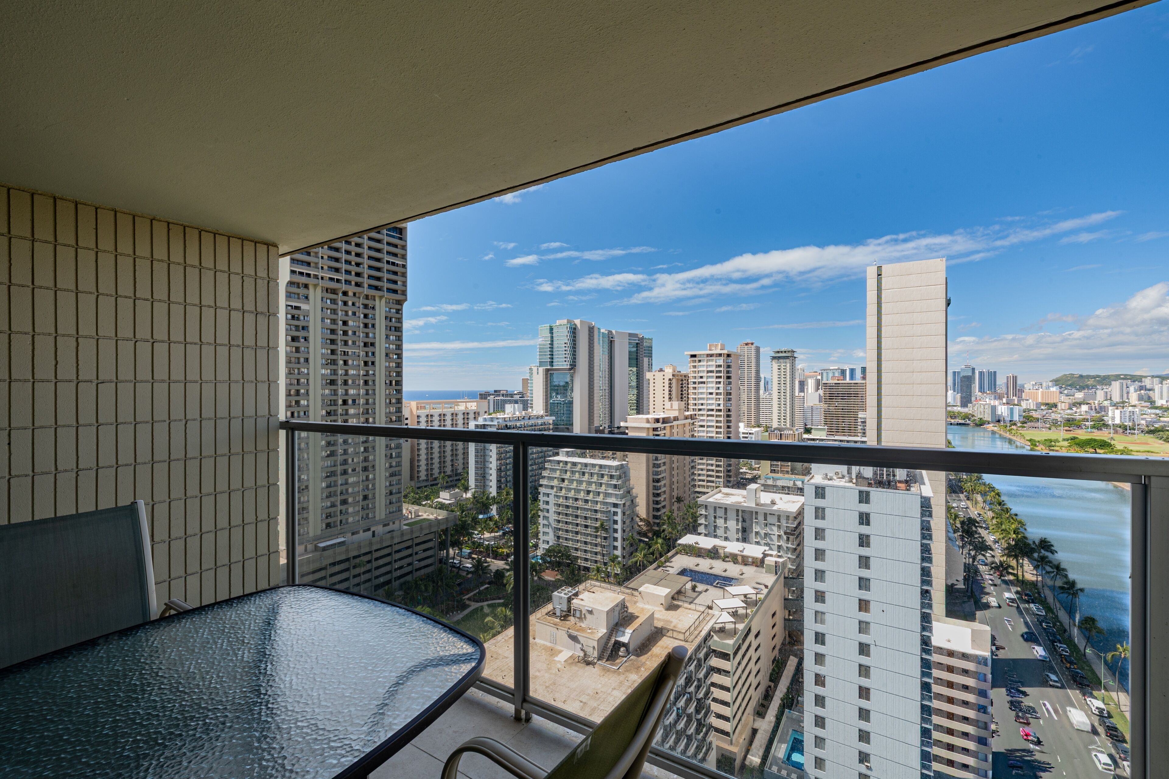 Un balcón con vistas a un paisaje urbano, que incluye rascacielos y una masa de agua.