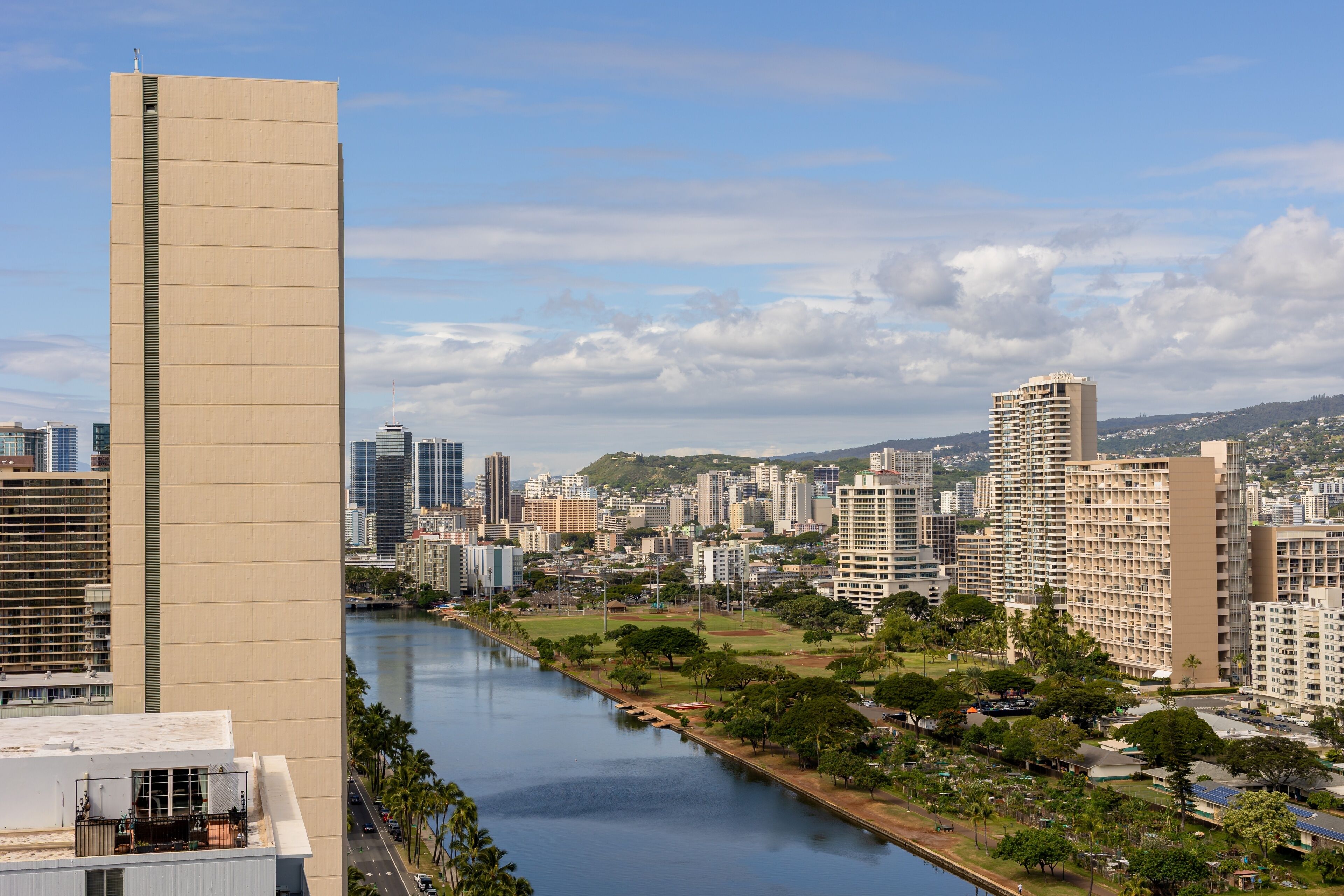 Un paisaje urbano con un río, edificios altos y una zona de parque.