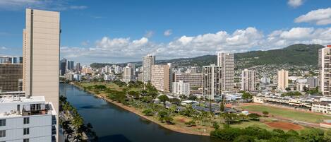 A cityscape with a river, high-rise buildings, and a park with a sports field.