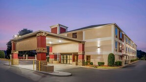 A multi-story hotel with a covered entrance, outdoor seating area, and landscaped garden. - Best Western Gardendale (Gardendale)