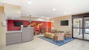 A hotel lobby with a reception desk, seating area, and a large glass door leading outside. - Best Western Gardendale (Gardendale)