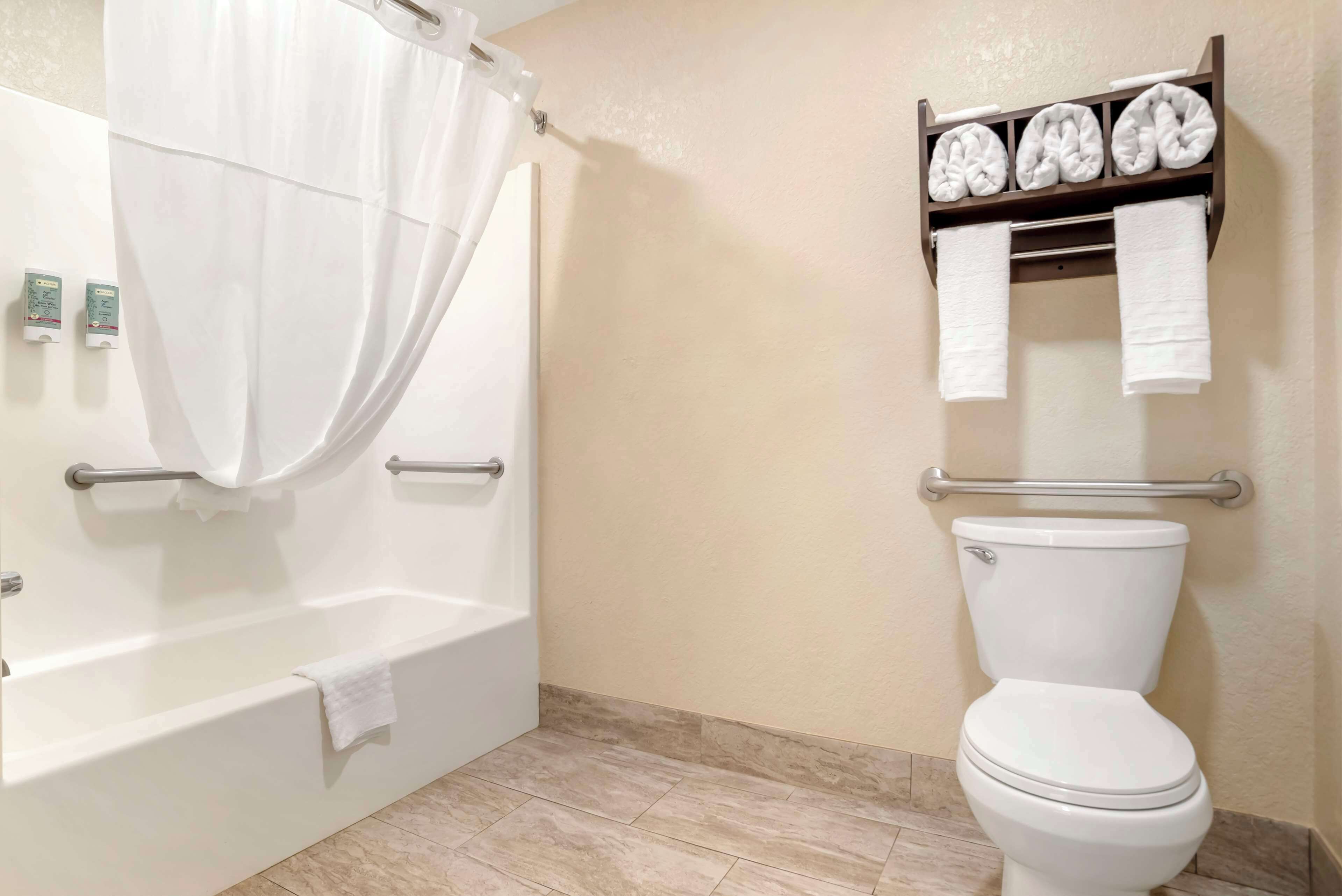 A bathroom with a bathtub, toilet, and a towel rack with folded towels.
