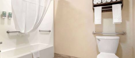 A bathroom with a bathtub, toilet, and a towel rack with folded towels.