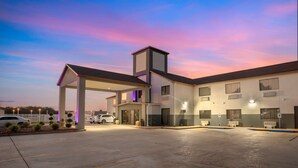 Un hotel moderno con entrada cubierta, varias ventanas y un estacionamiento.
