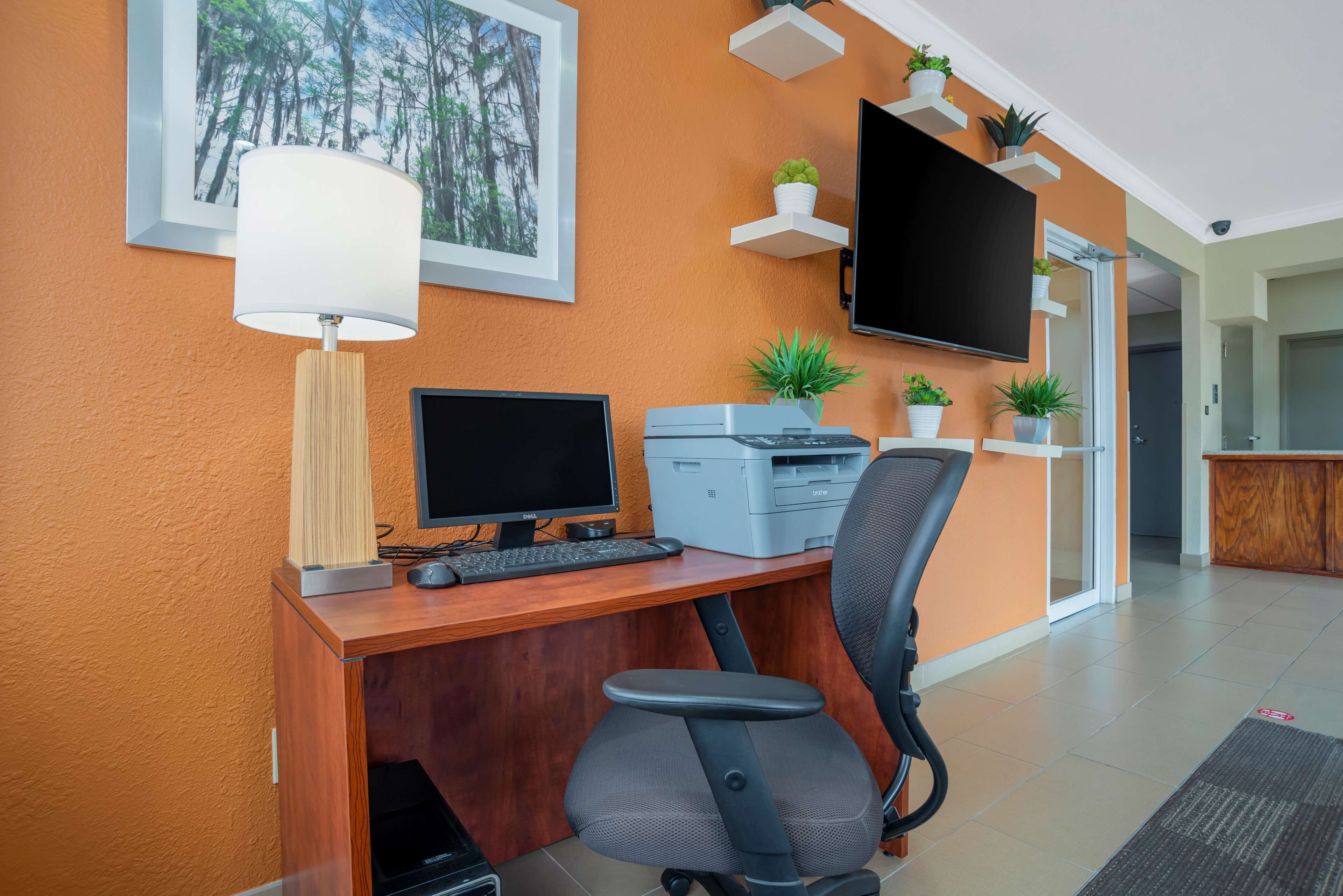 Un espacio de oficina moderno con un escritorio de madera, computadora, impresora y silla ergonómica.