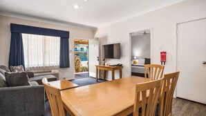 Una sala de estar moderna con un sofá, una mesa de comedor de madera y un televisor.