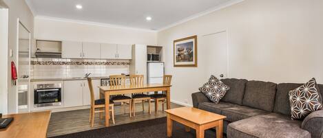 A compact living space with a kitchenette, dining area, and a sofa.