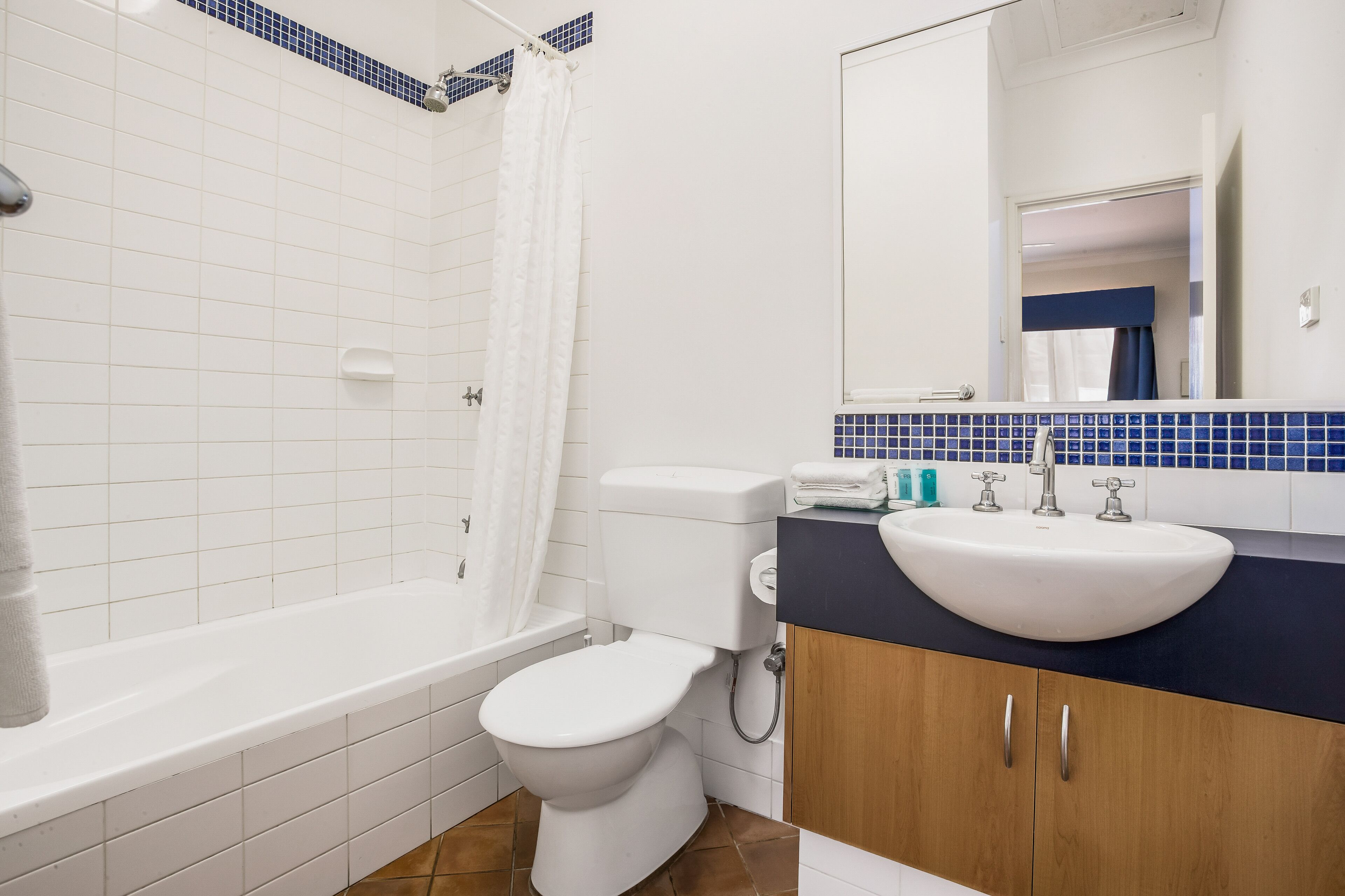 Une salle de bain avec une baignoire blanche, des toilettes et un lavabo doté d’un plan de travail bleu.