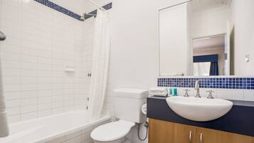 Une salle de bain avec une baignoire blanche, des toilettes et un lavabo doté d’un plan de travail bleu.