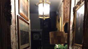 A narrow hallway with ornate wallpaper, a chandelier, and framed artwork on the walls. - The Pavilion Hotel (London)