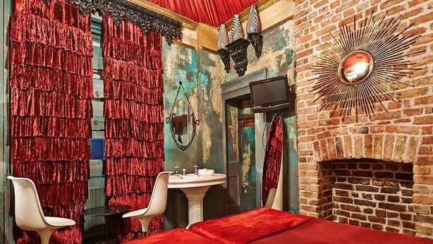 A room with a brick fireplace, a mirror, a television, and red curtains. - The Pavilion Hotel (London)