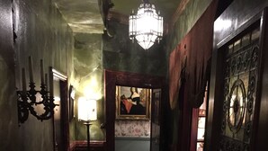 A dimly lit hallway with a patterned carpet, a chandelier, and a fire exit sign. - The Pavilion Hotel (London)