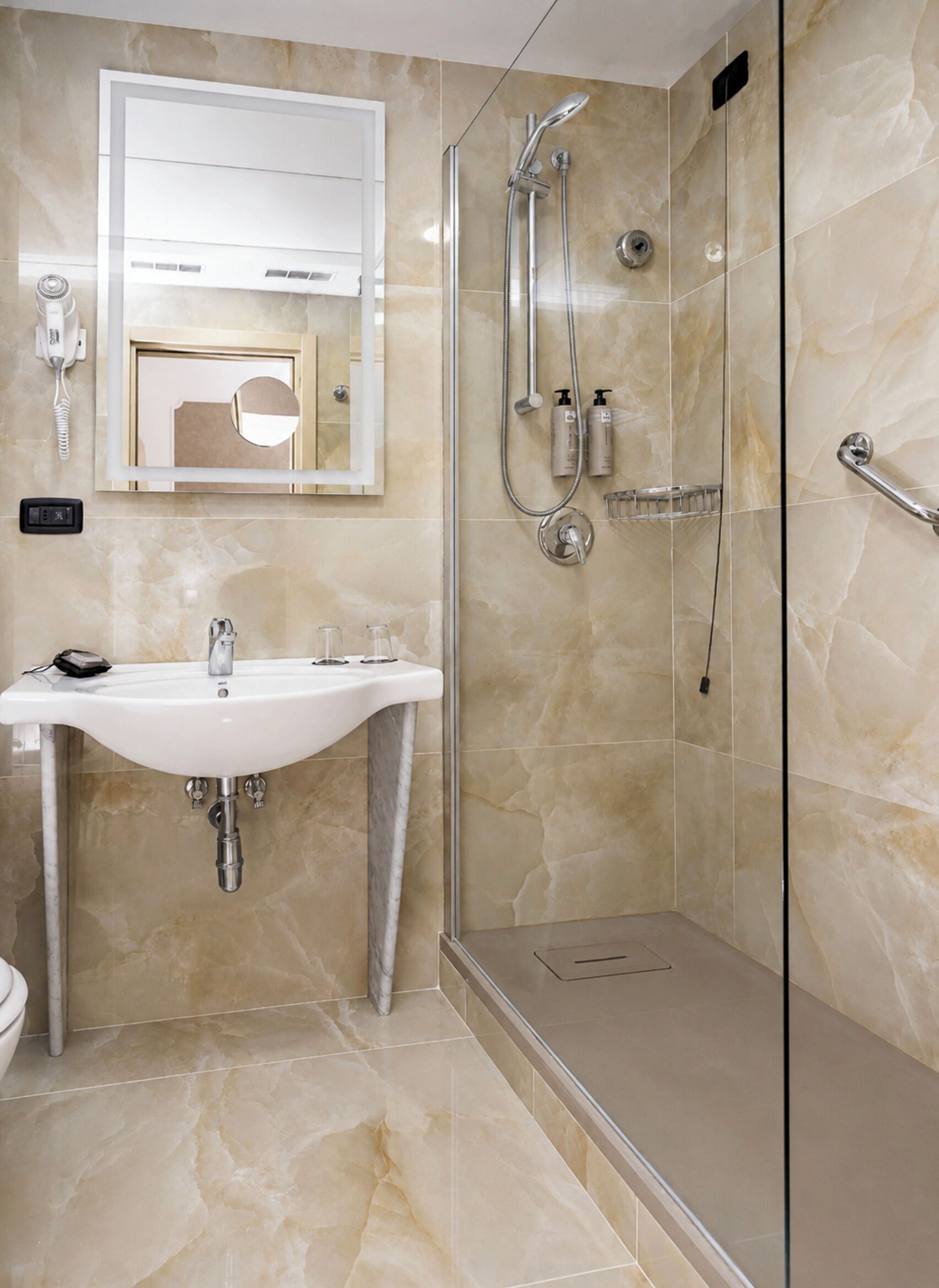 Een moderne badkamer met een douche met glazen wand, een wastafel met spiegel erboven en een toilet.
