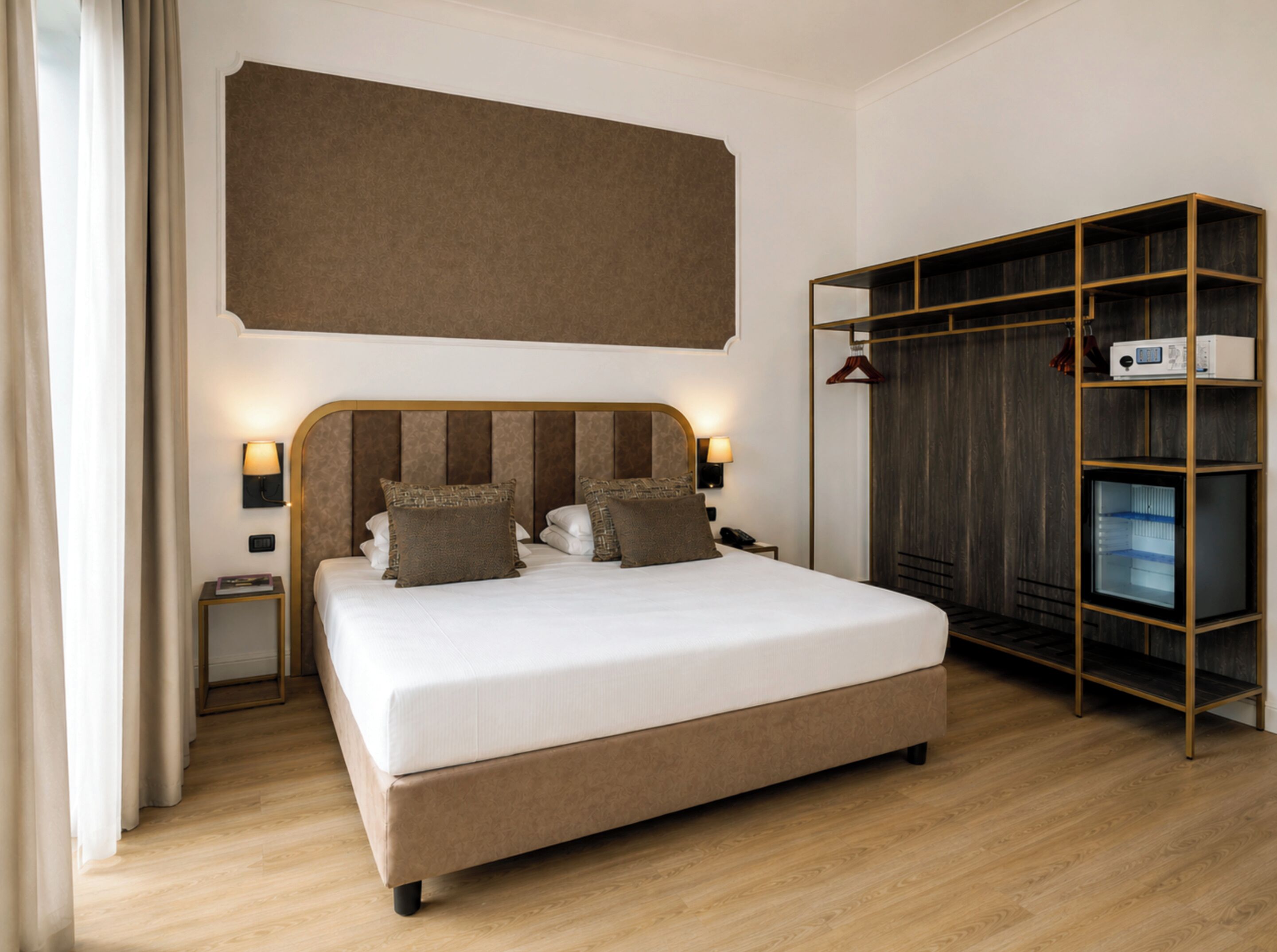 A hotel room with a large bed, bedside lamps, a wardrobe, and a television.