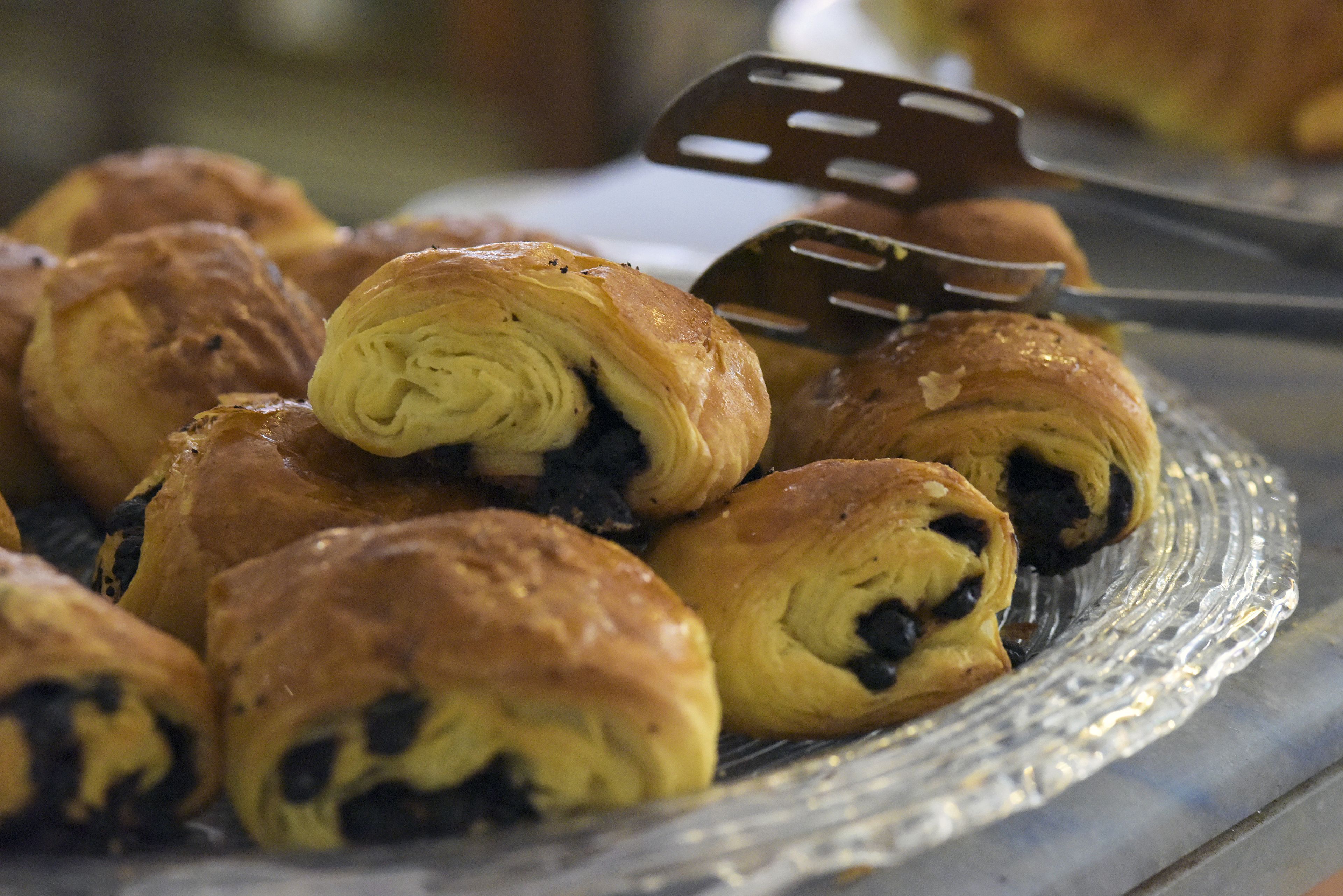 Une assiette de viennoiseries, comprenant des croissants et une pâtisserie enroulée, accompagnée d'une spatule de service.