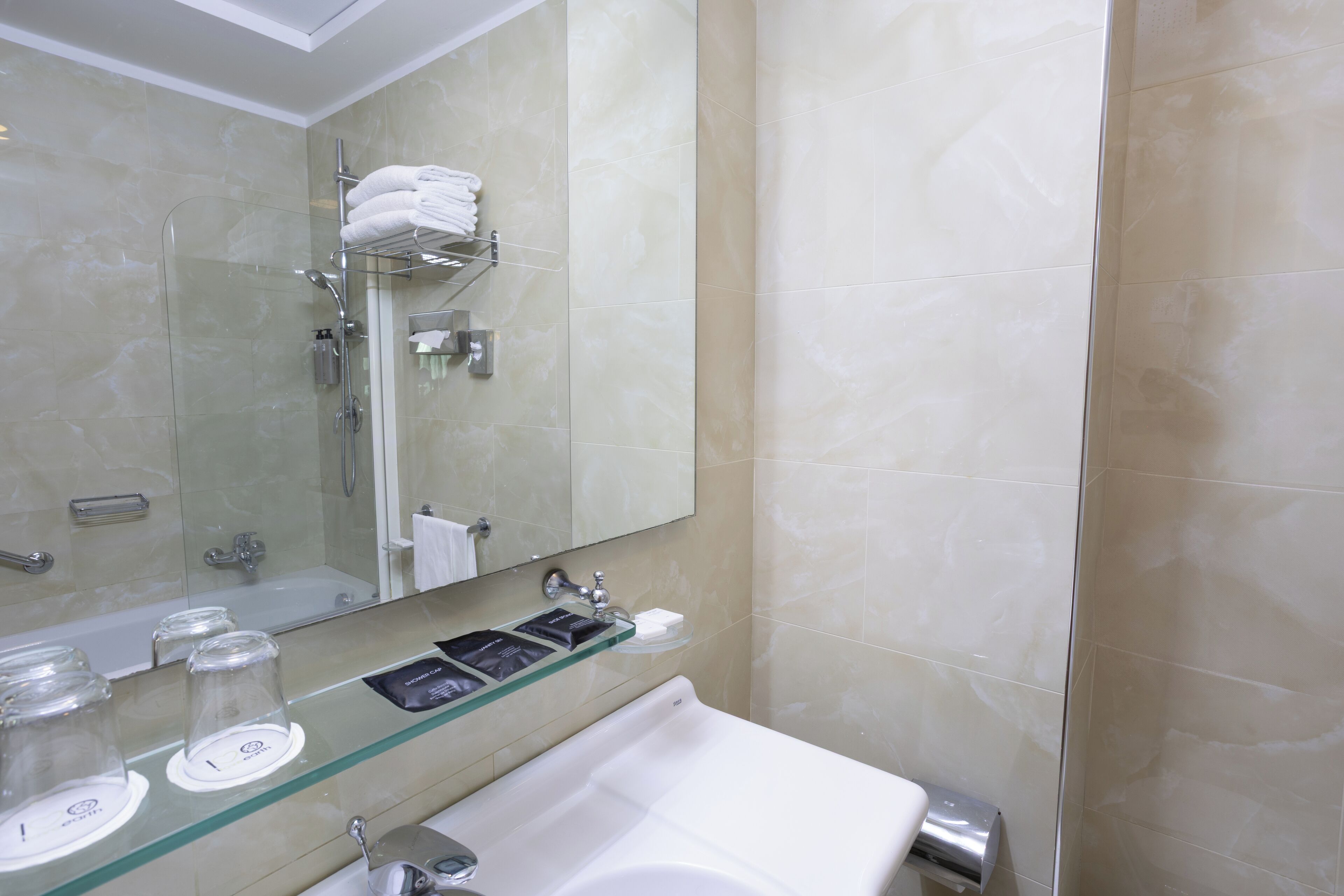 A bathroom with a glass shower enclosure, a white sink, and a mirror above the sink.