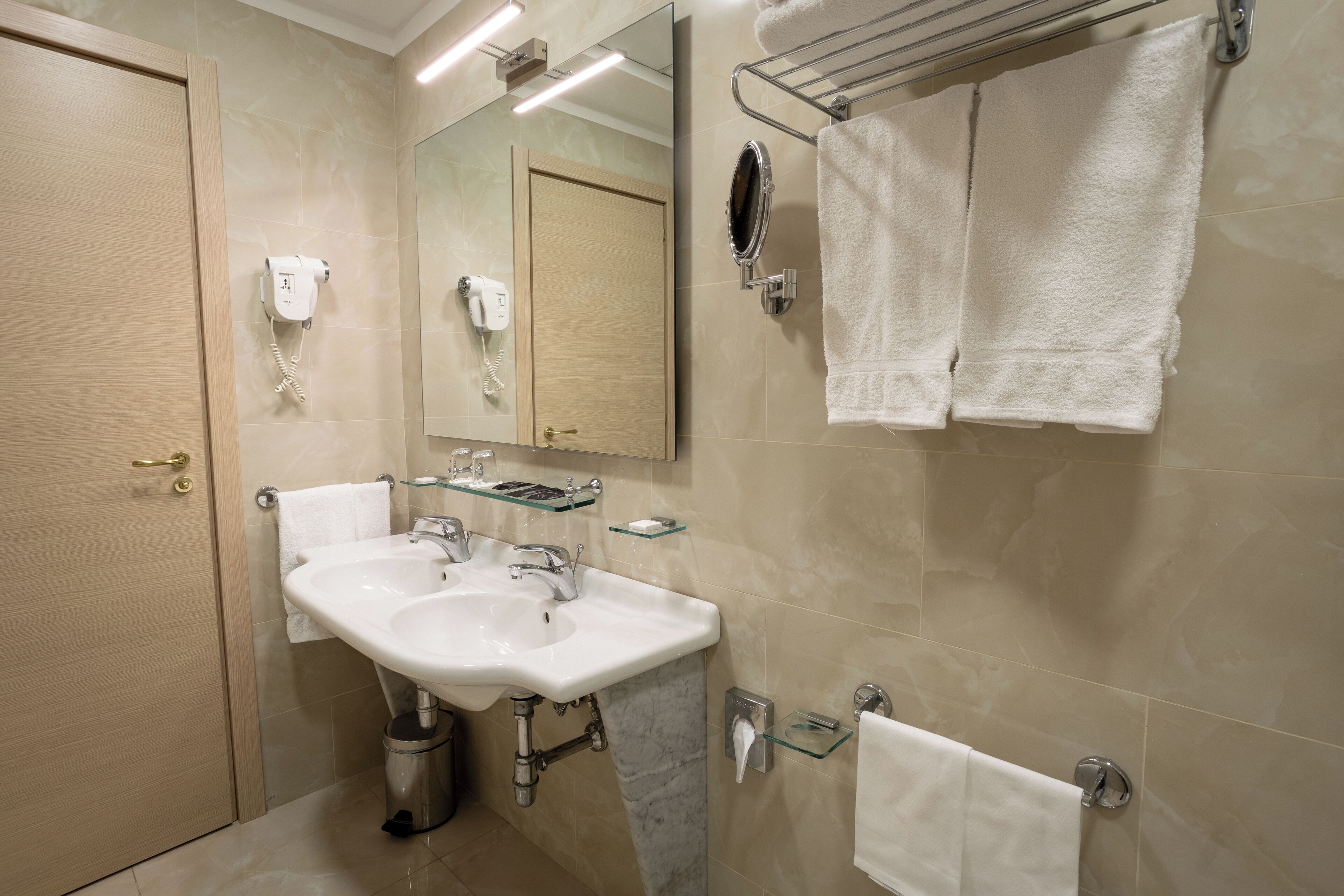 A modern bathroom with a sink, mirror, towel rack, and hair dryer.