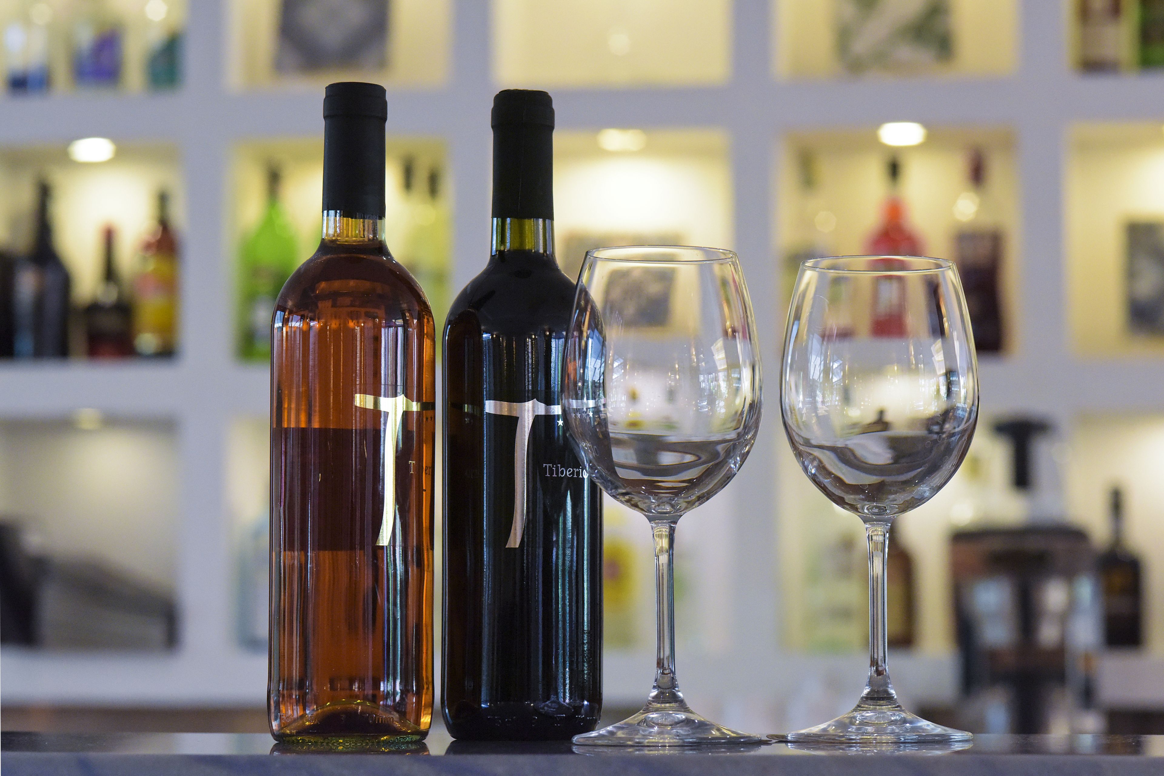 Two bottles and two glasses on a bar counter.