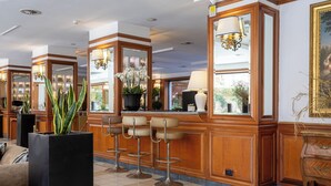 A lobby with a bar area, seating, and a large mirror. - Grand Hotel Tiberio (Rome)