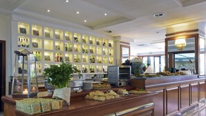 A buffet area with a variety of food items, a display of liquor bottles, and a large potted plant. - Grand Hotel Tiberio (Rome)