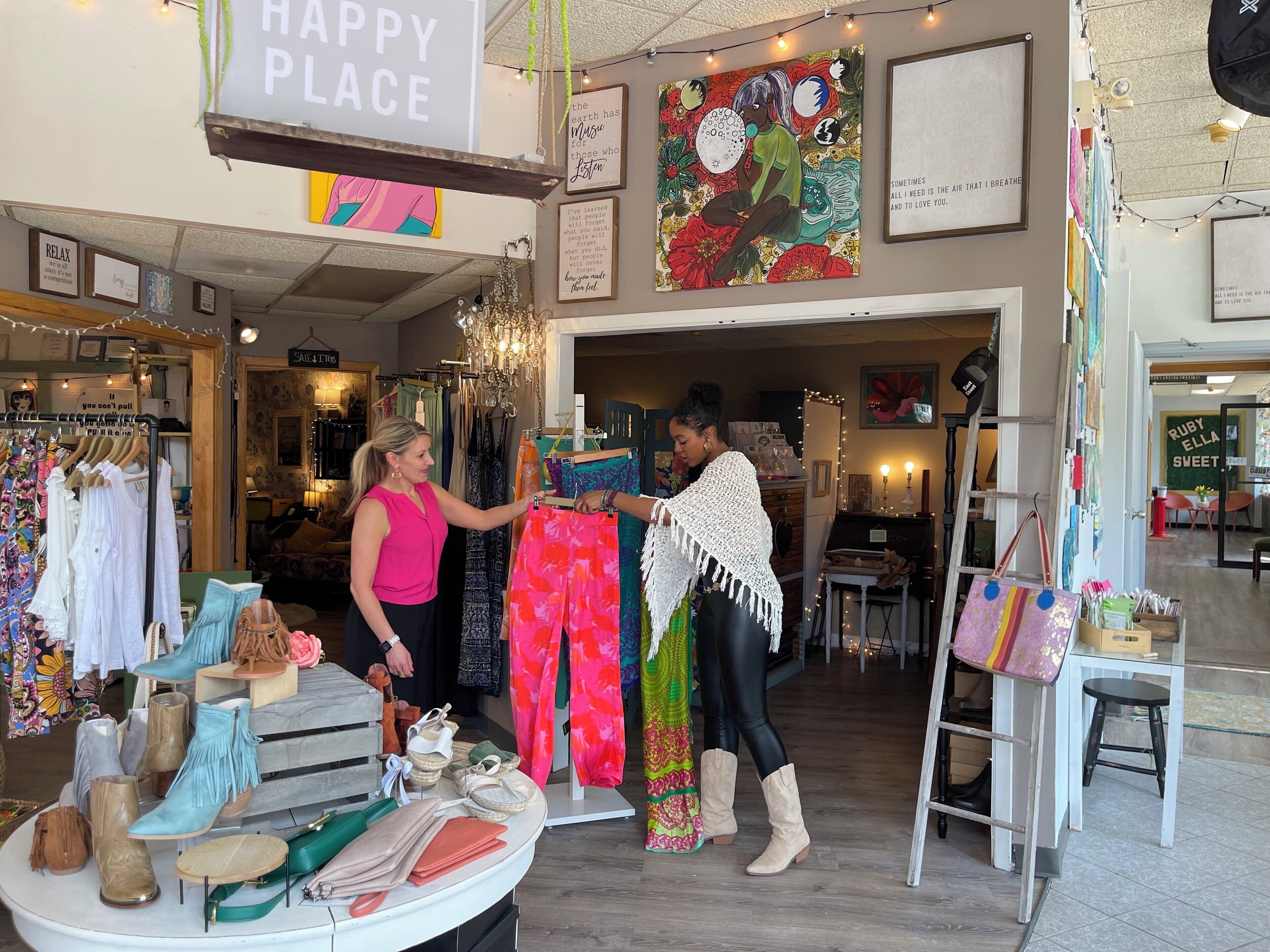 A boutique clothing store with racks of colorful clothing and a display of shoes.