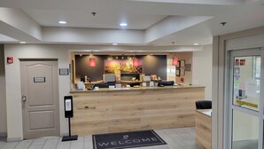 A reception area with a wooden counter, a 'Welcome' mat, and a 'Staff Only' door. - Country Inn & Suites by Radisson, McDonough, GA (McDonough)