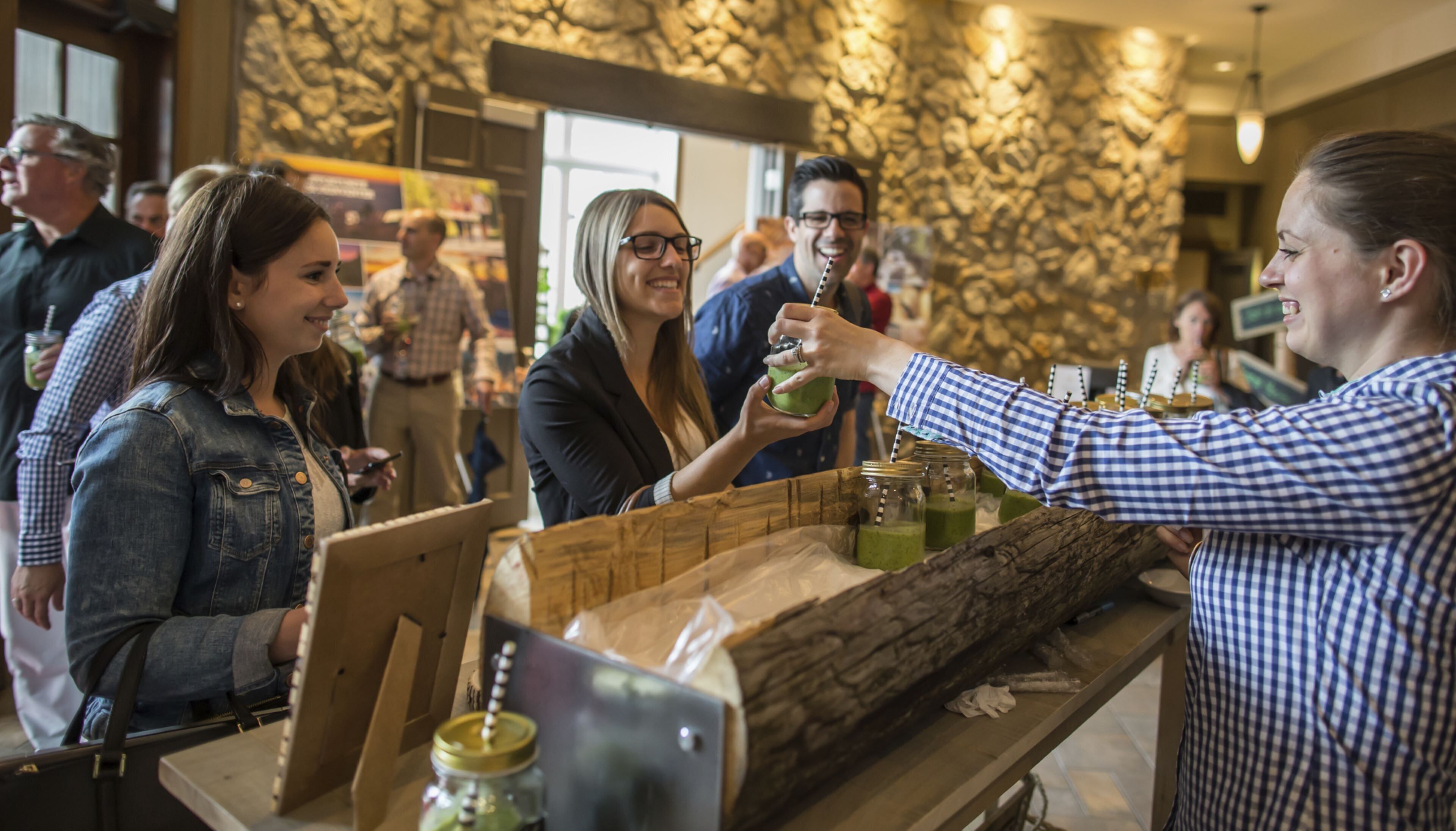 Un espace bar avec un comptoir, un présentoir en bois et une foule de personnes.