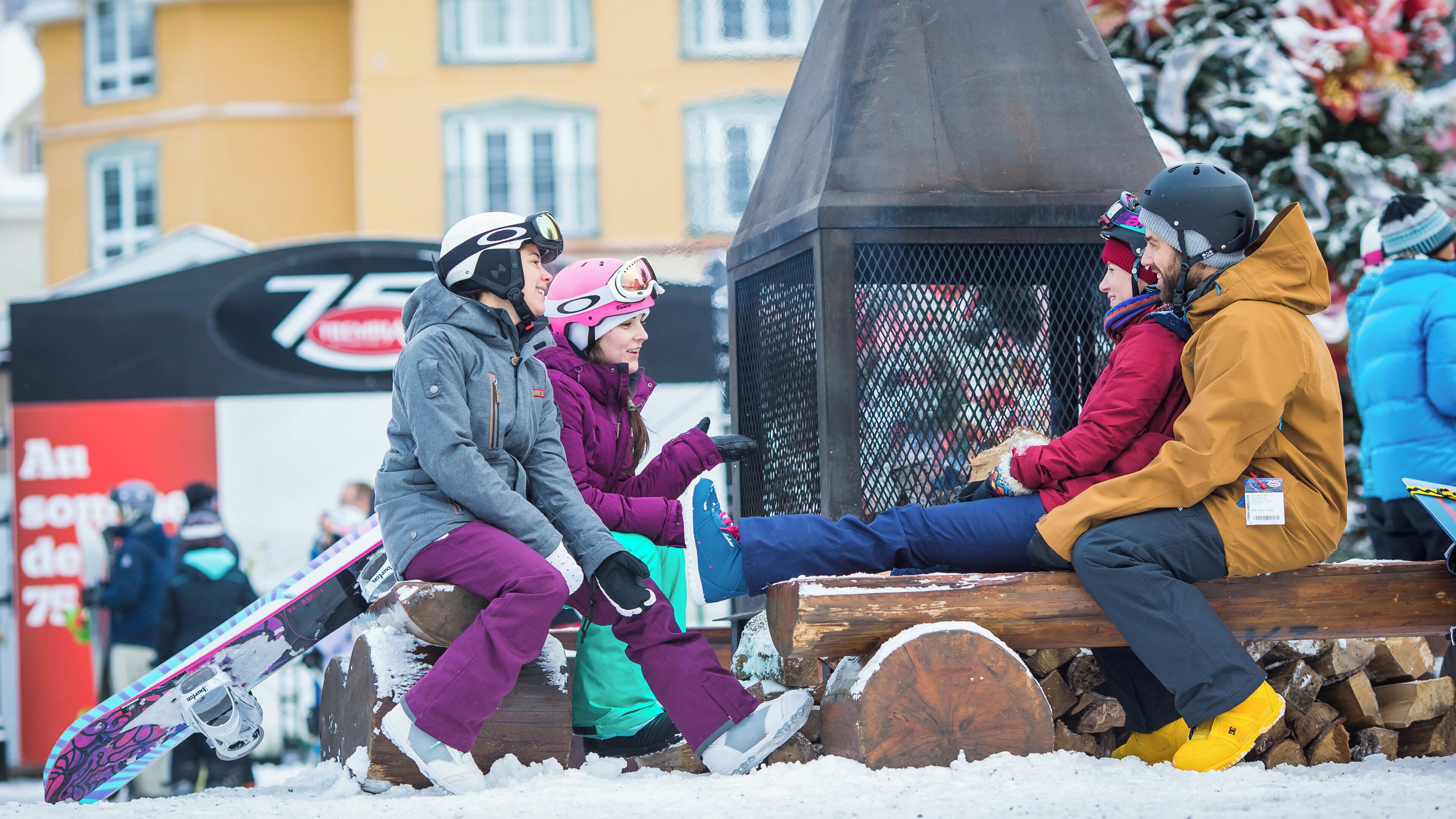 A group of people sitting on a wooden bench in a snowy outdoor setting.
