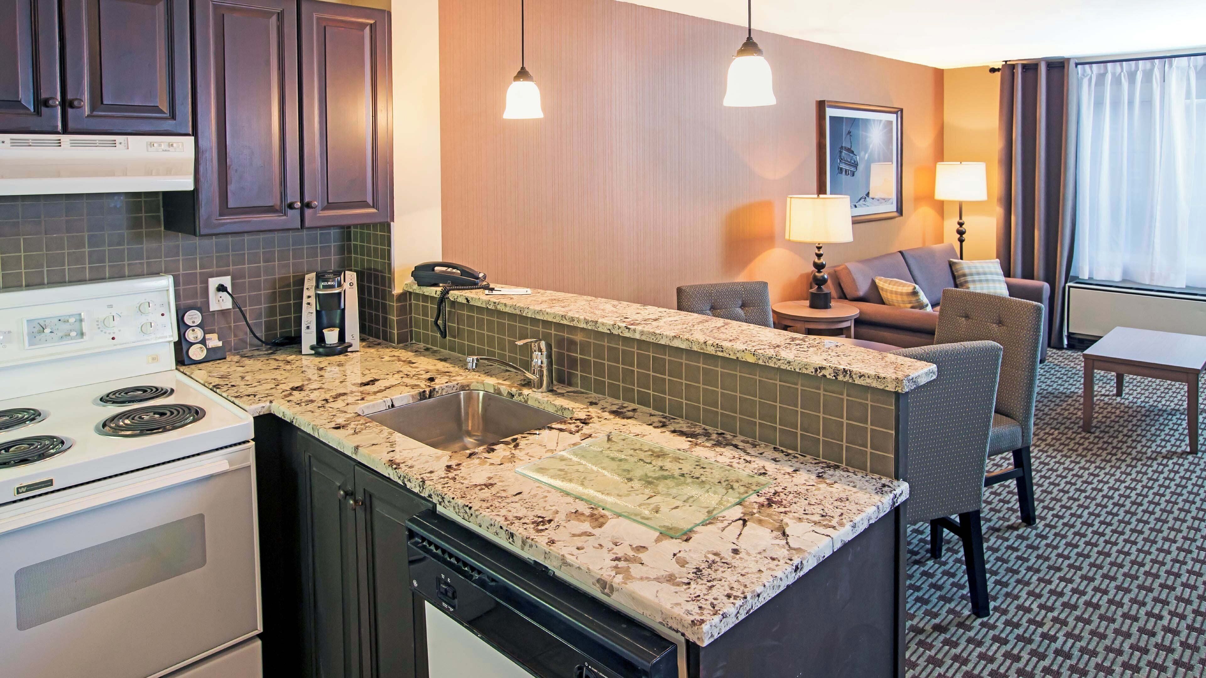 A compact kitchen with a built-in stove, a sink, and a coffee maker.