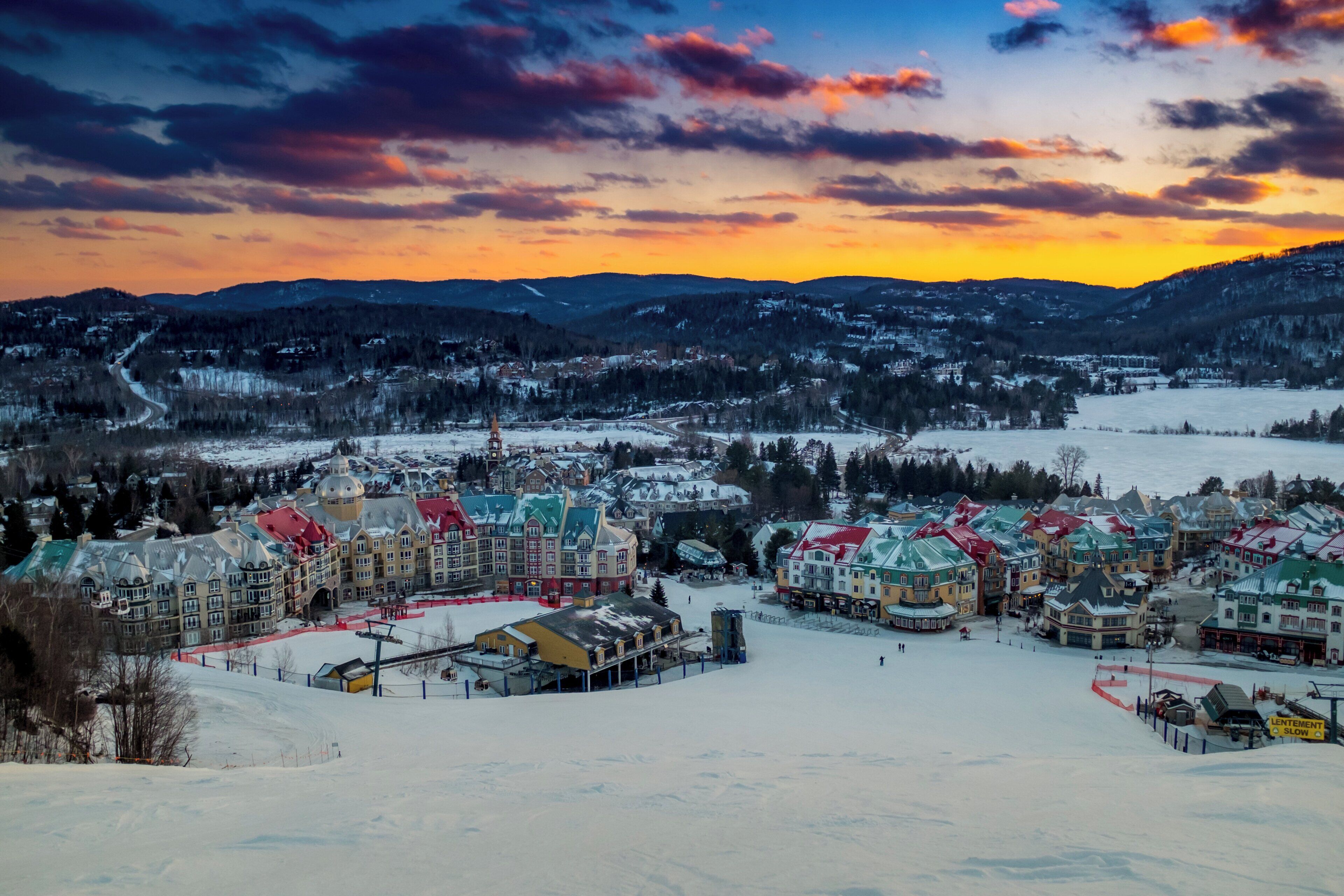 A snow-covered town with a variety of buildings, including a prominent hotel with a red roof.