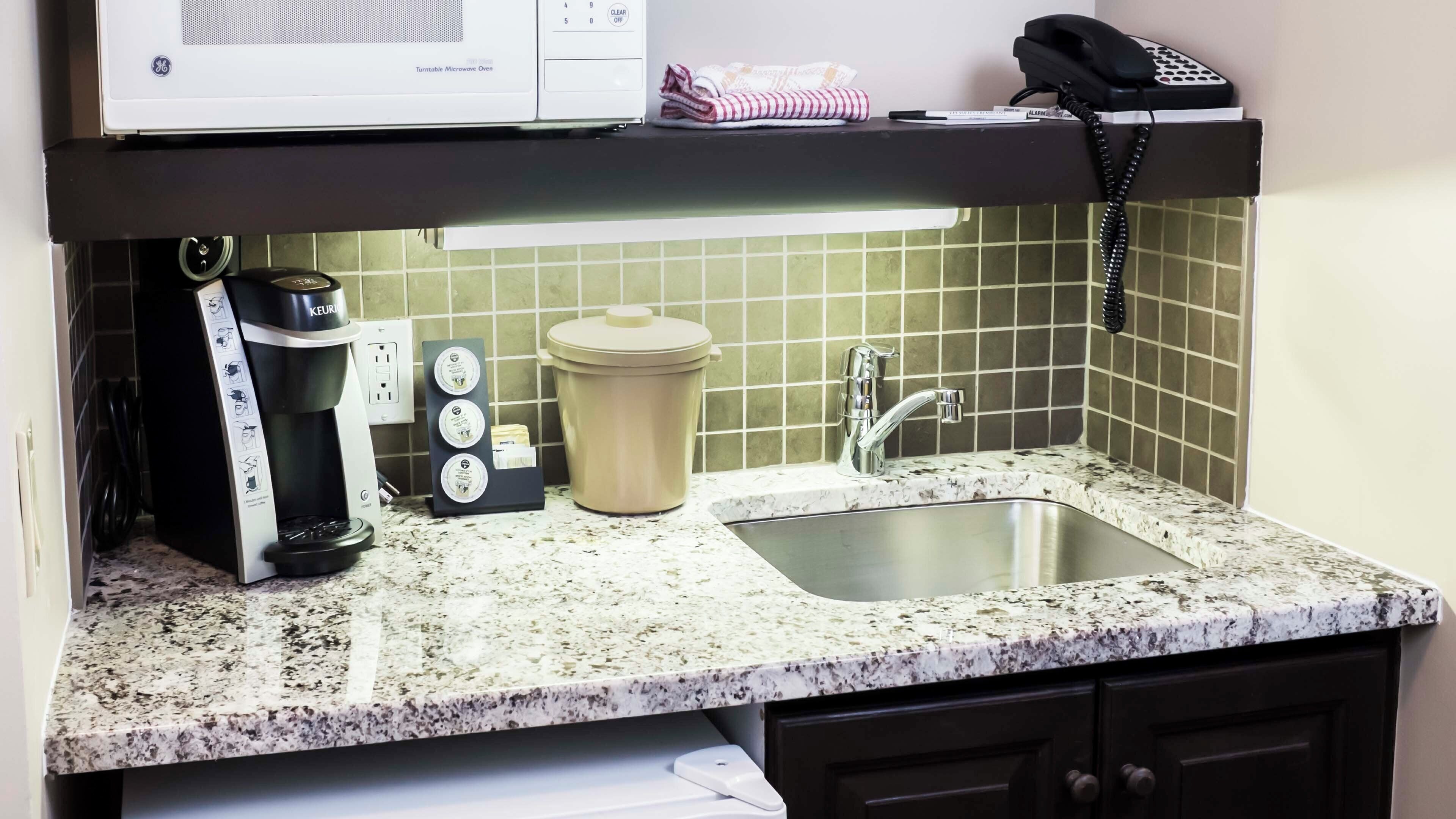 A kitchen with a sink, a coffee maker, a microwave, and a kettle.