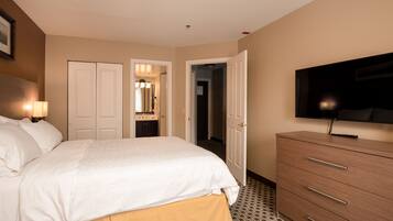 Habitación de hotel con cama, cómoda, televisión y baño visible a través de una puerta abierta.