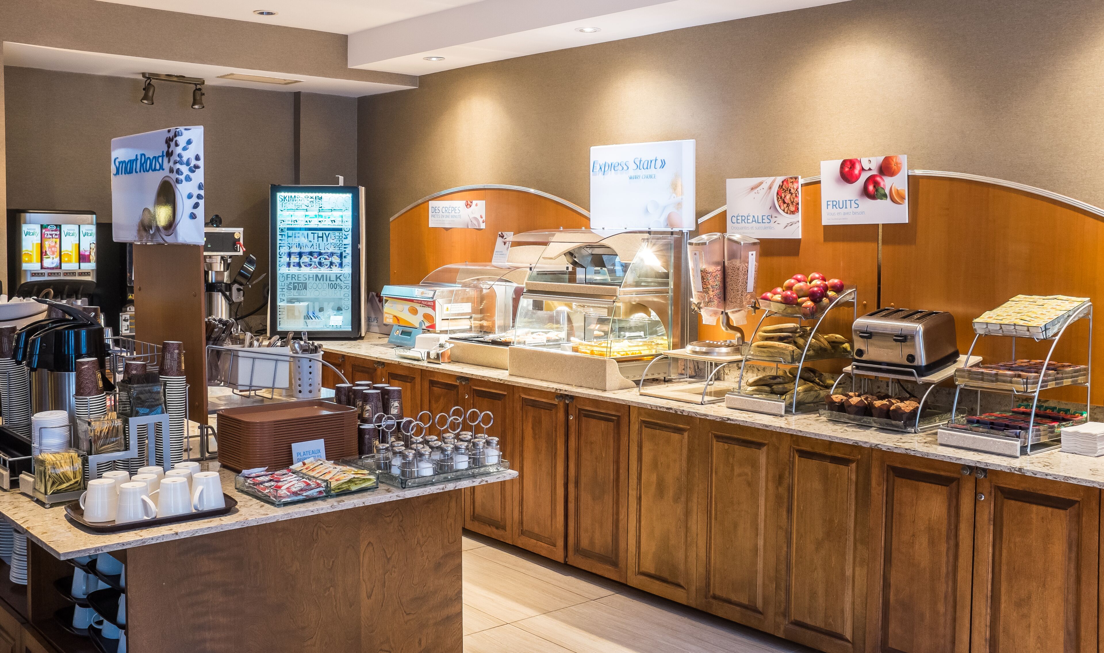 A breakfast buffet with various food options, including cereals, fruits, and a coffee station.