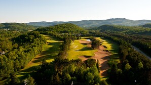 A golf course with a lake, surrounded by forested hills. - Holiday Inn Express and Suites Tremblant by IHG (Mont-Tremblant)