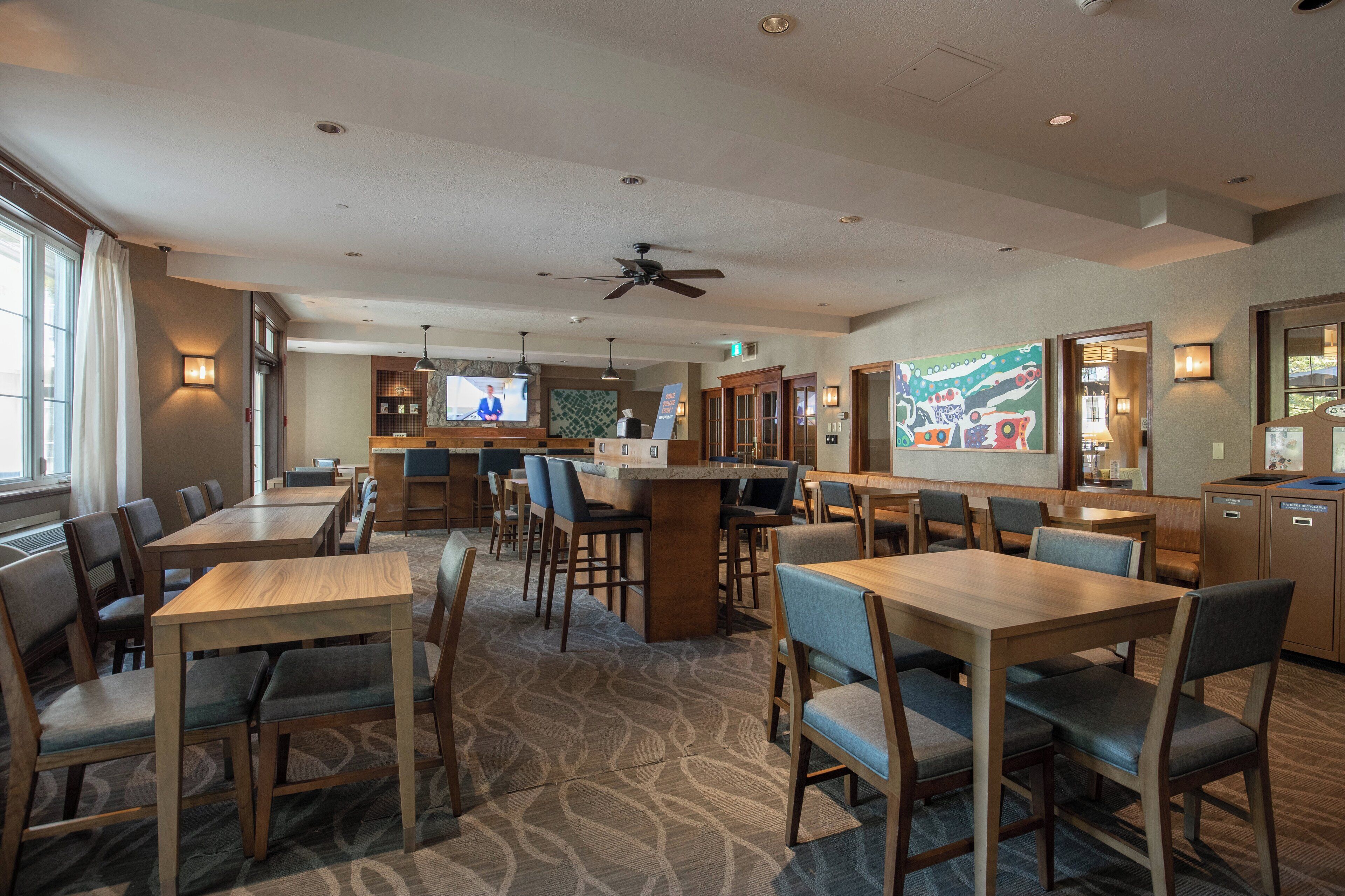 A hotel lobby with multiple seating areas, a reception desk, and a television screen.