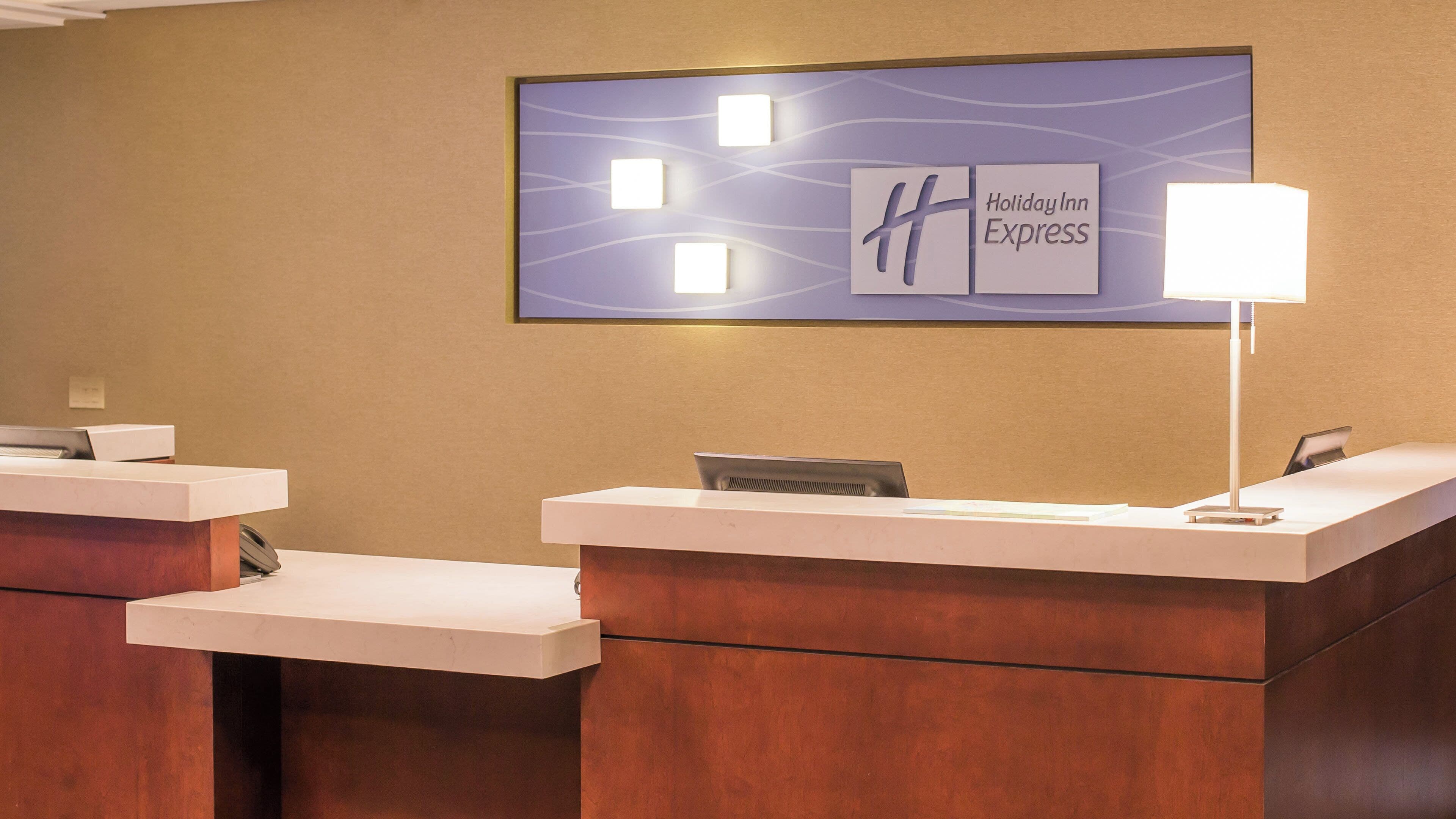 Una recepció d'hotel amb el rètol de Holiday Inn Express, una làmpada d'escriptori i un telèfon.
