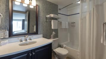 Une salle de bain équipée d’un lavabo, d’un miroir, d’un porte-serviettes, de toilettes et d’un espace douche.