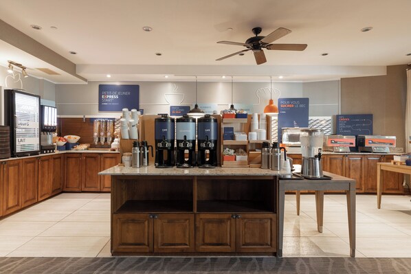 Un área de cocina moderna con estación de café, armarios de madera y ventilador de techo.