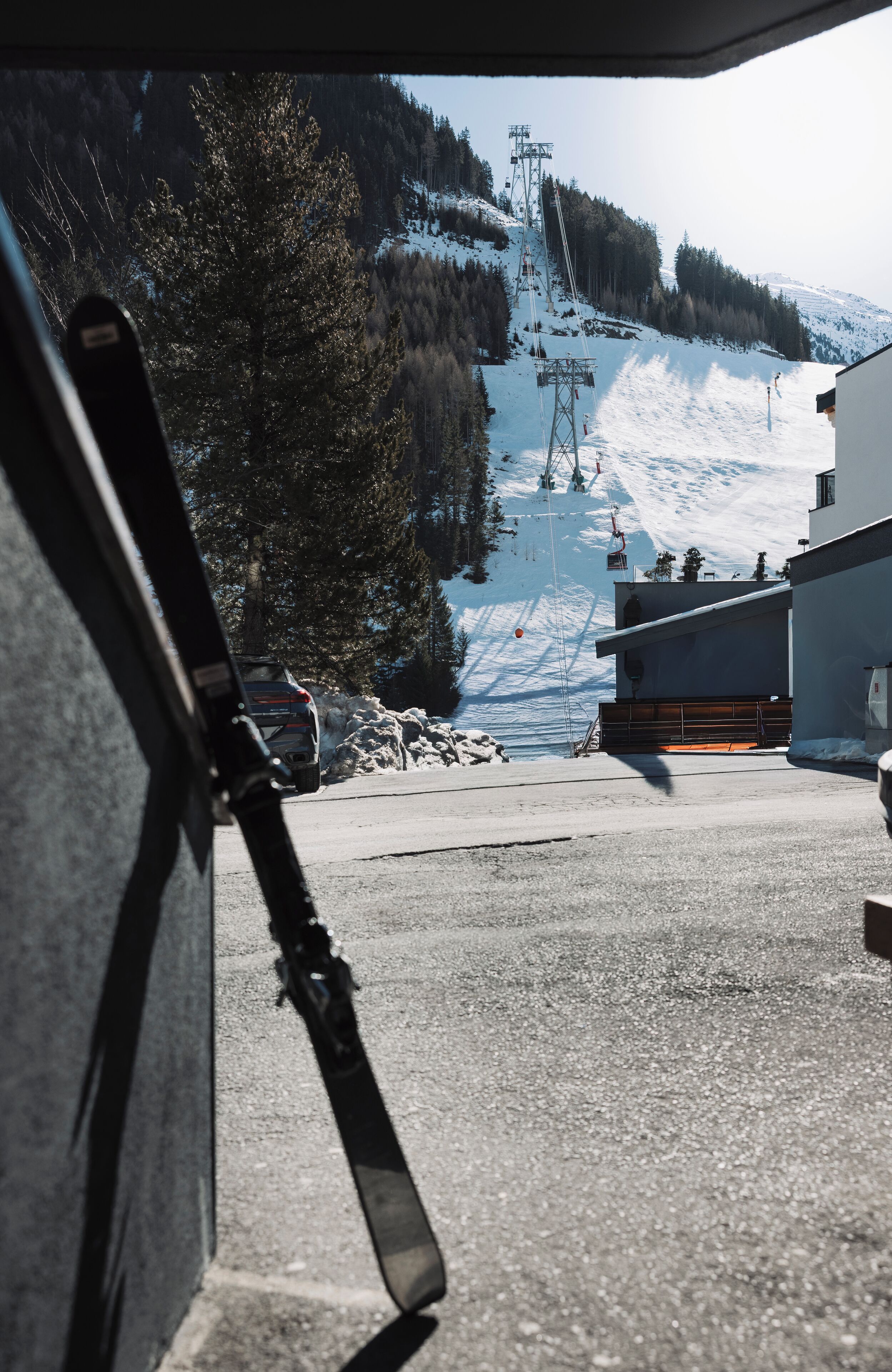 A ski lift, a mountain, and a building with a ski slope in the background.