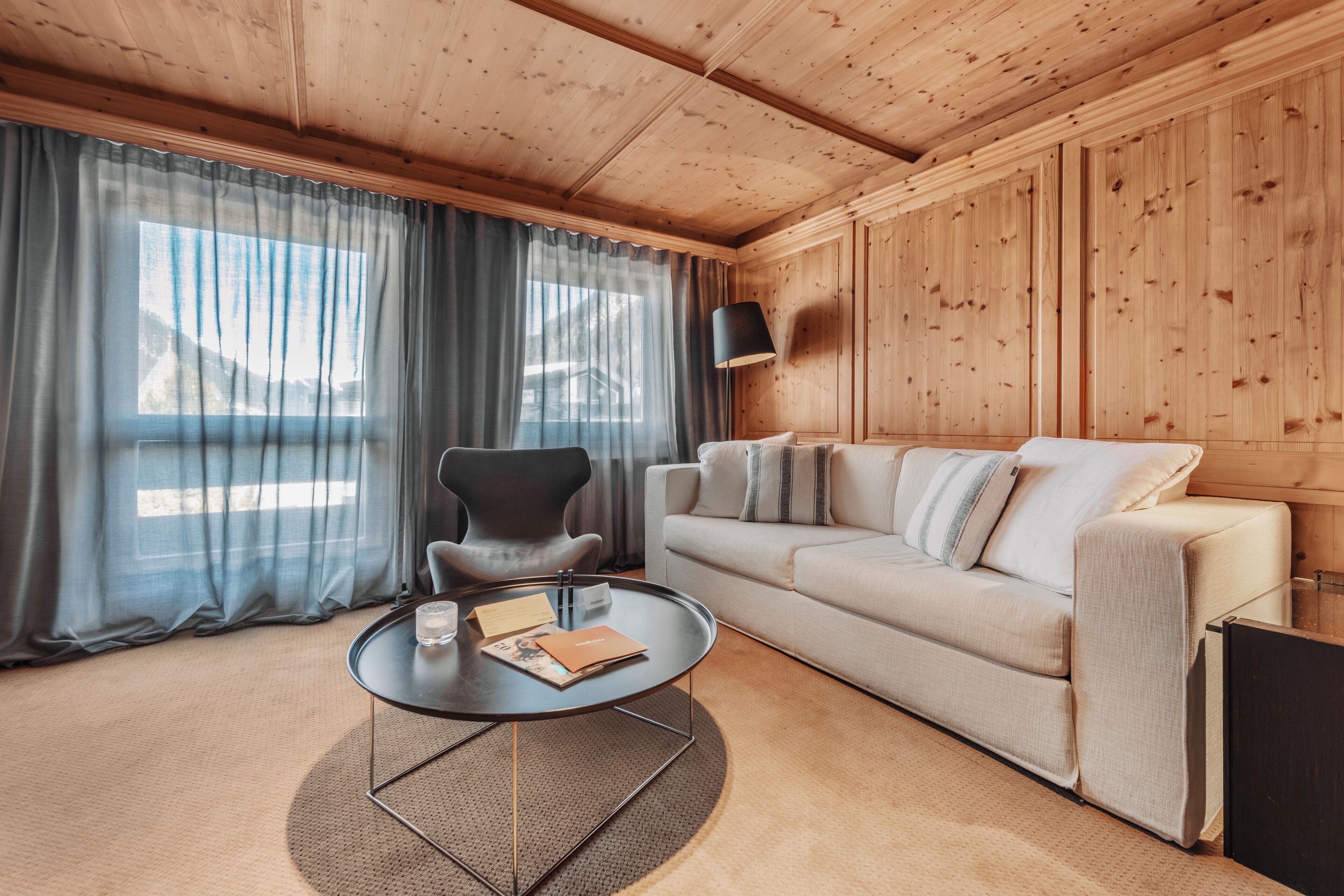 A wooden-paneled room with a sofa, a round coffee table, and a lamp.