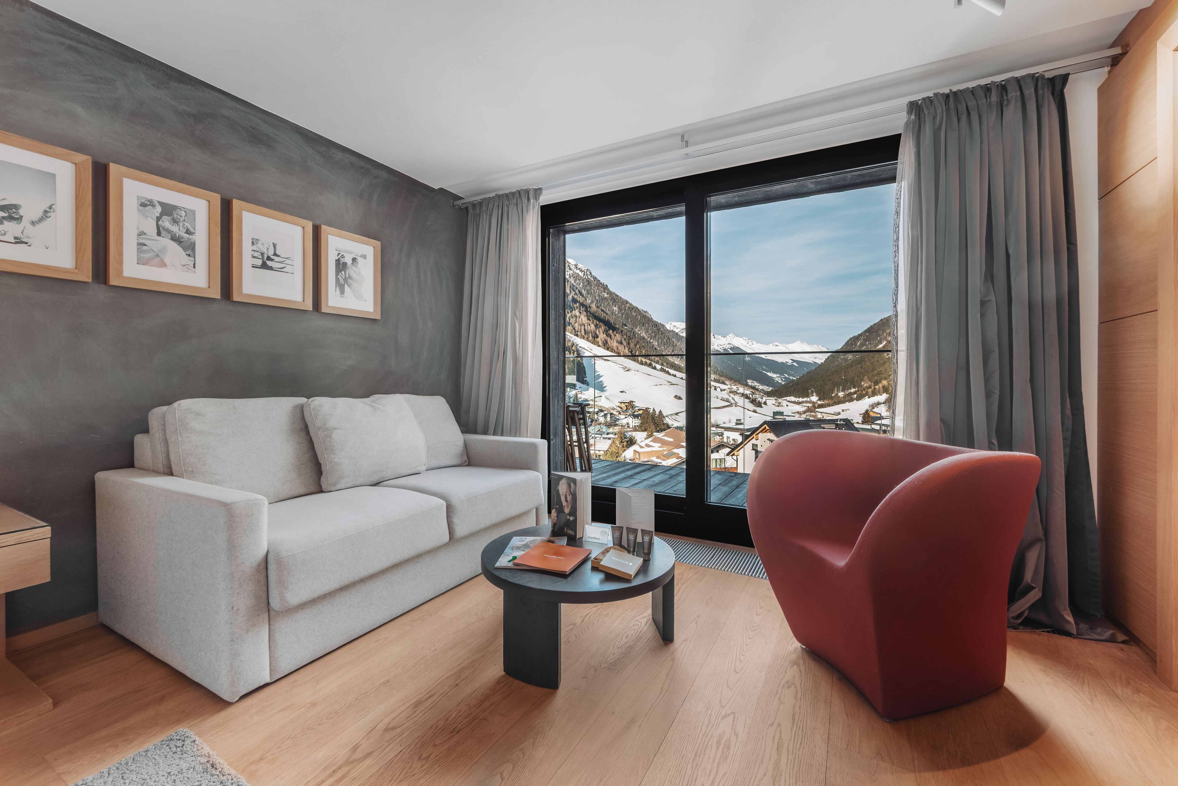 A modern living room with a sofa, a red armchair, a coffee table, and framed pictures on the wall.
