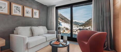 A modern living room with a sofa, a red armchair, a coffee table, and framed pictures on the wall.