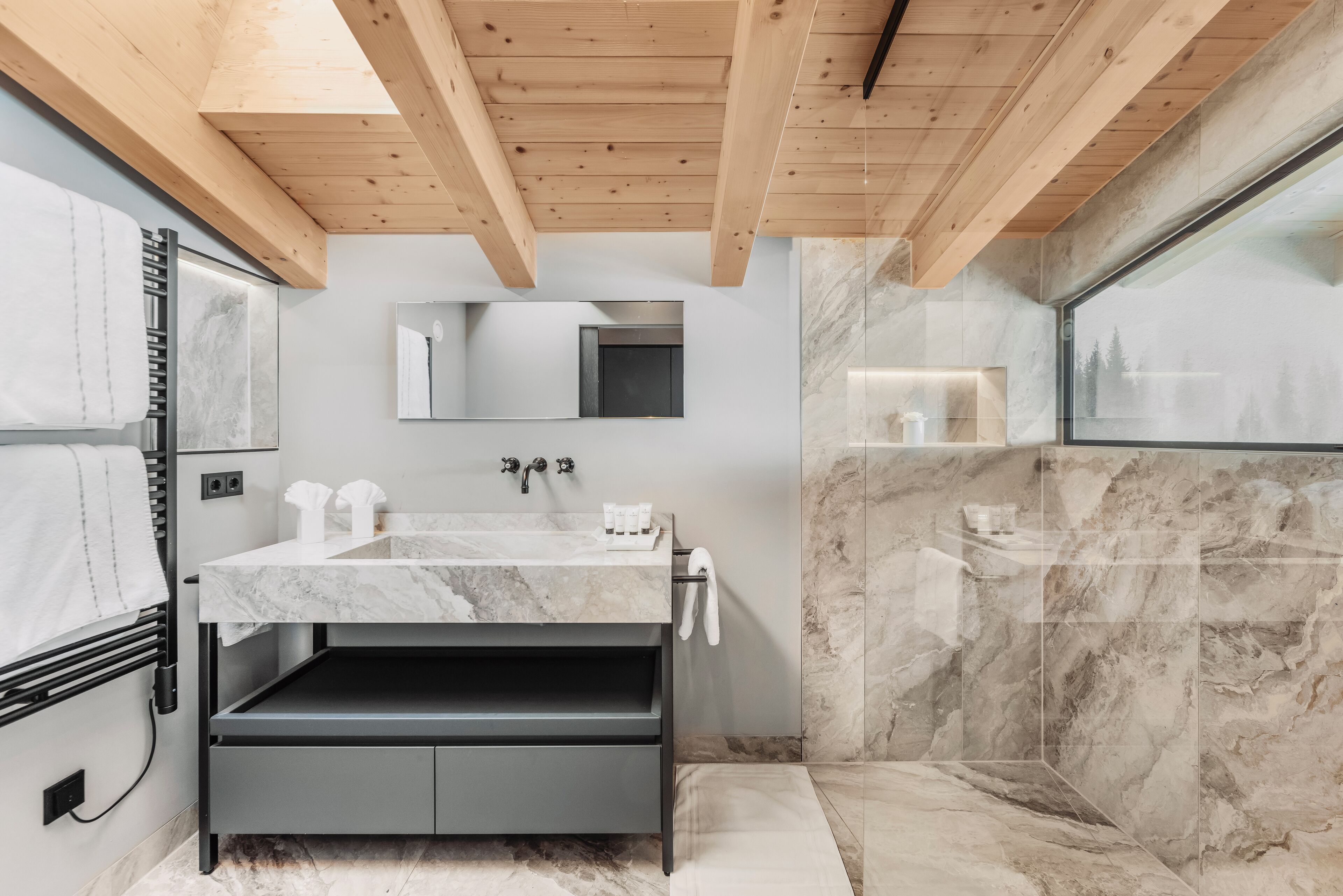 A modern bathroom with a marble sink, a mirror, and a shower area.