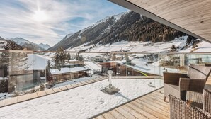 Un edificio moderno con un balcón de vidrio que ofrece vistas a un paisaje montañoso nevado.