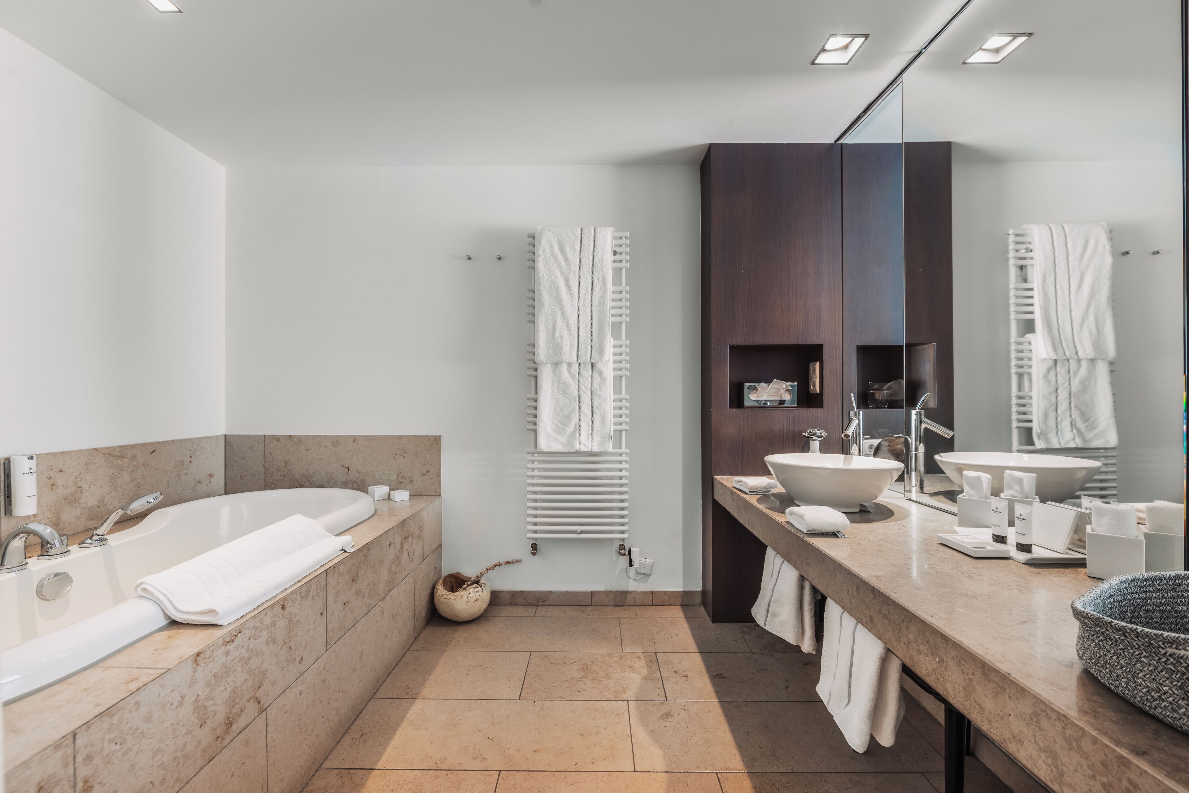 A modern bathroom with a large bathtub, two sinks, a vanity, and a mirror.