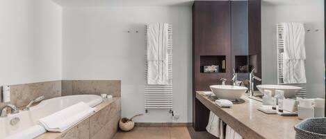 Ein modernes Badezimmer mit einer großen Badewanne, zwei Waschbecken, einem Waschtisch und einem Spiegel.