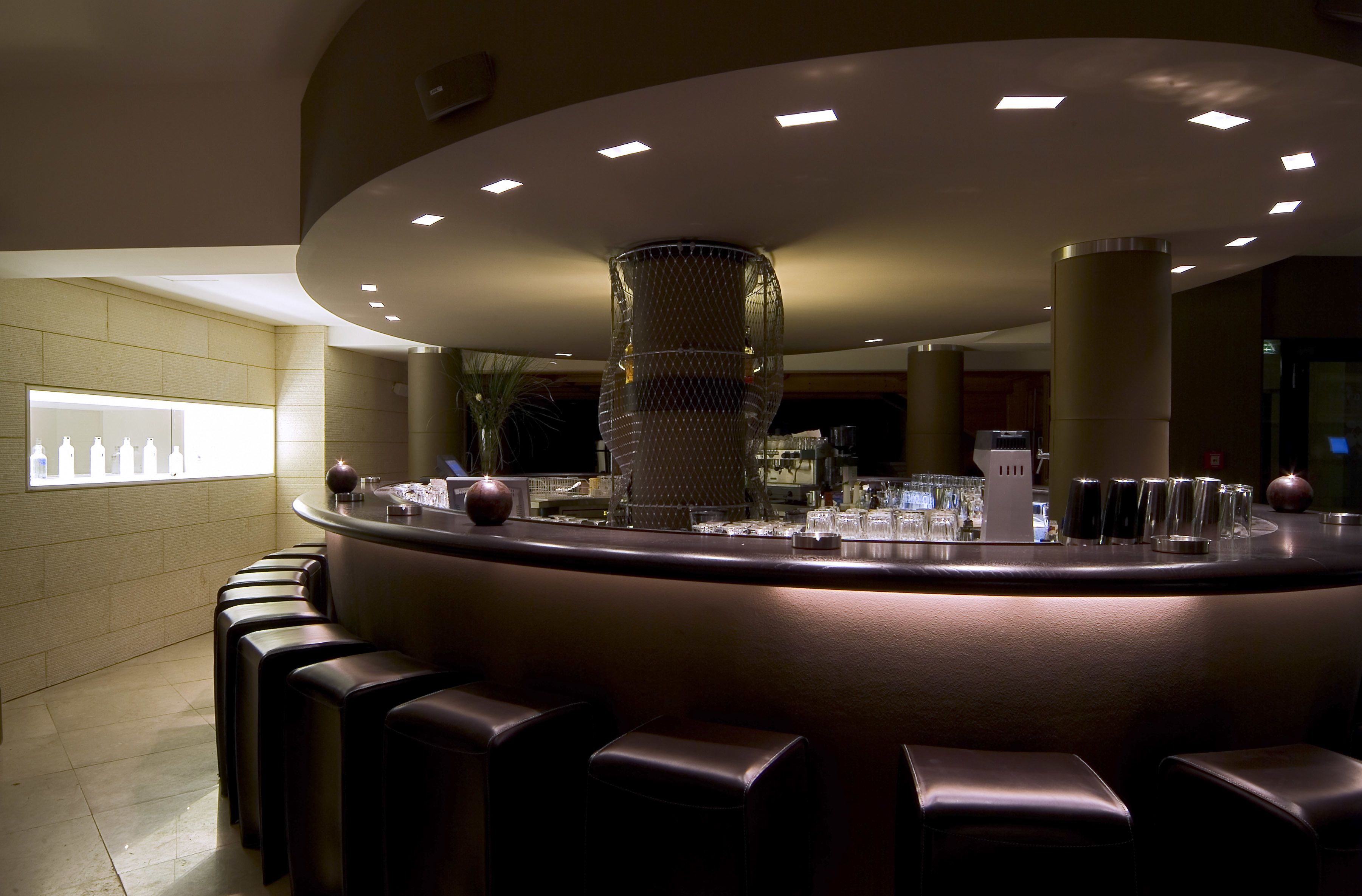 A bar area with a curved counter, multiple stools, and a decorative metal structure.