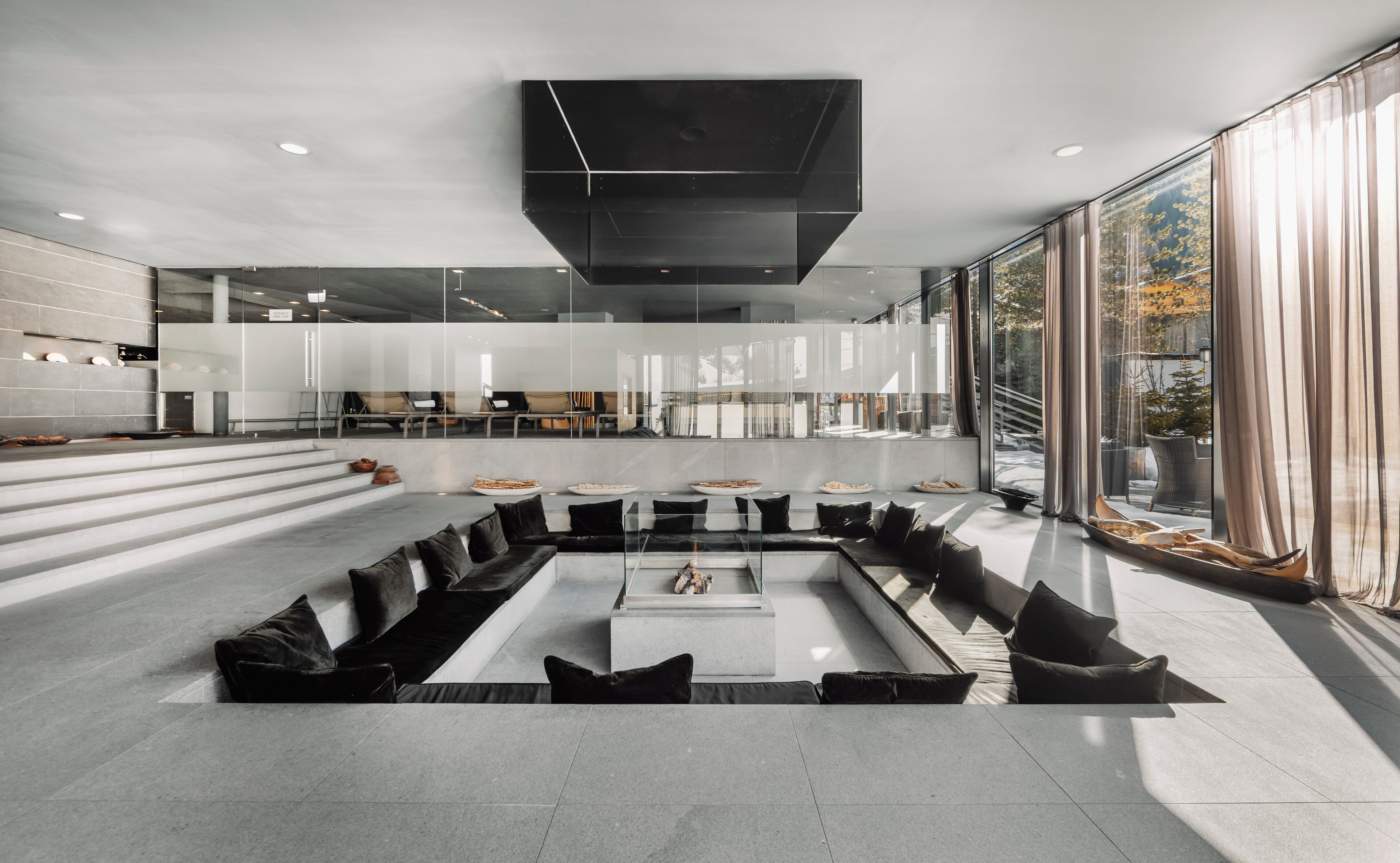 Ein modernes Interieur mit einer zentralen Sitzecke, großen Fenstern und einem minimalistischen Design.