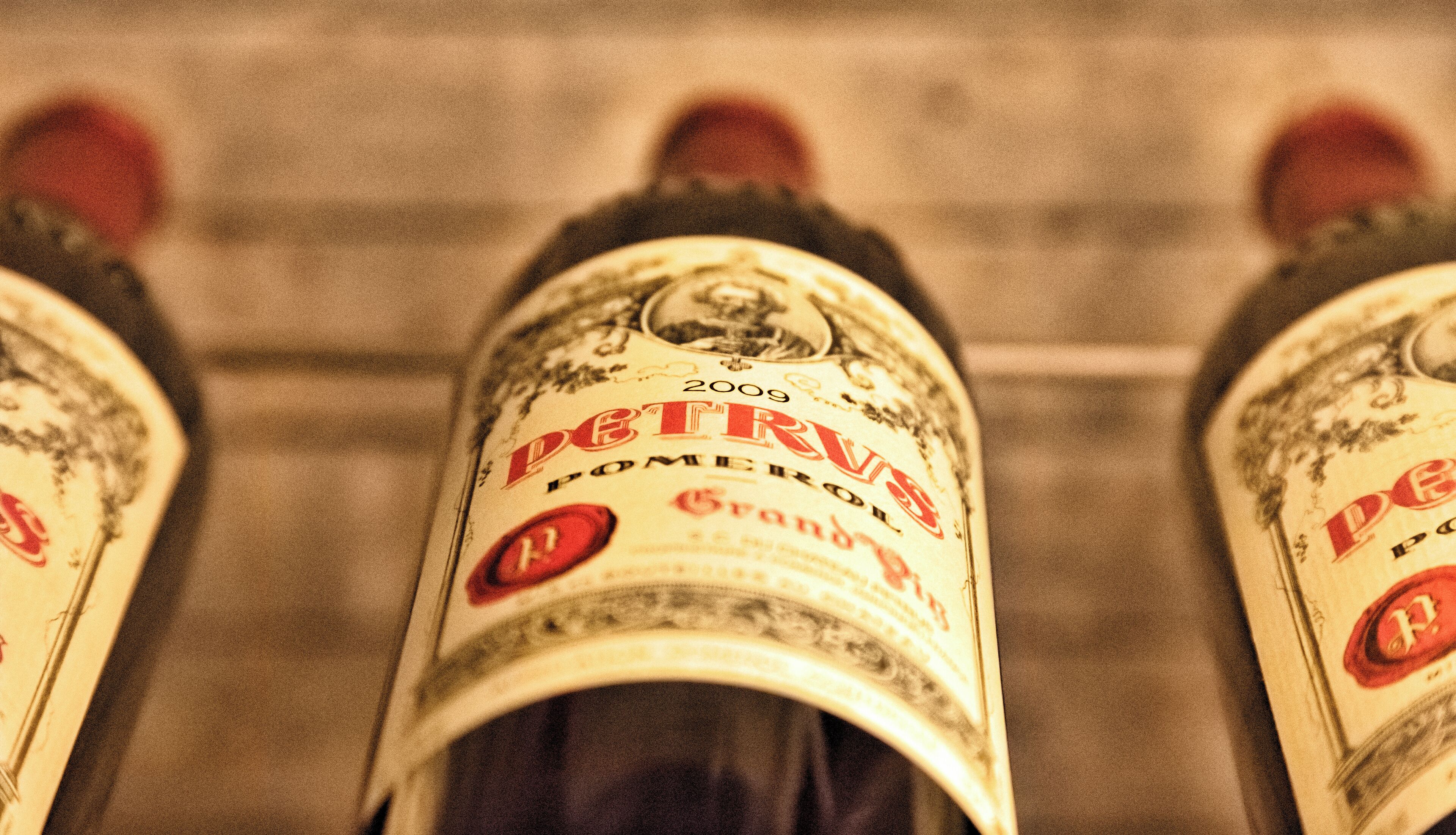 A close-up of a bottle with the label "PETRUS" and the year "2009".